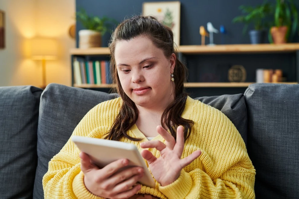 Disabled girl with down syndrome using iPad to contact Fawn Assistive Care