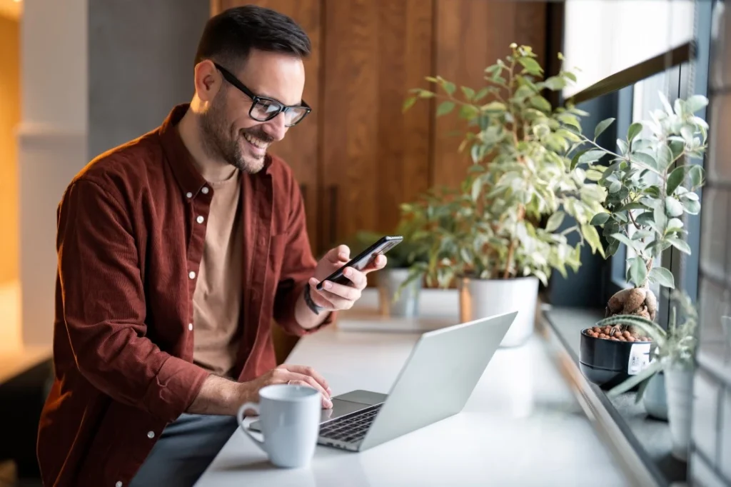 Happy man sitting at desk with laptop making NDIS referral