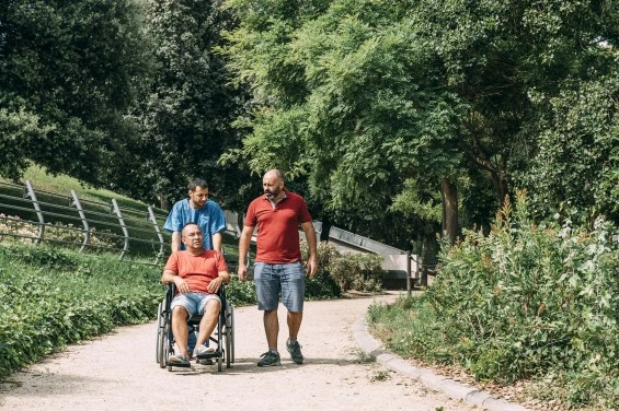Disabled man in wheelchair outside with carers